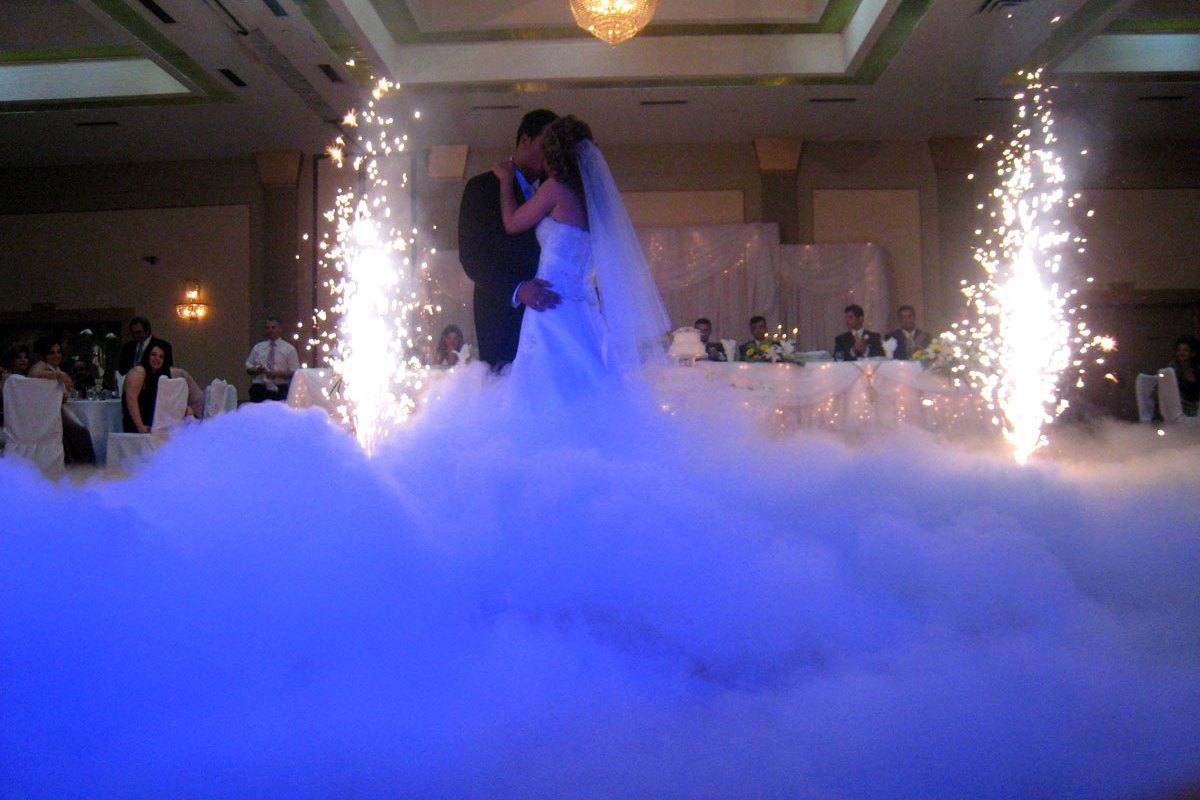 A newlywed couple sharing their first dance above a soft layer of cloud