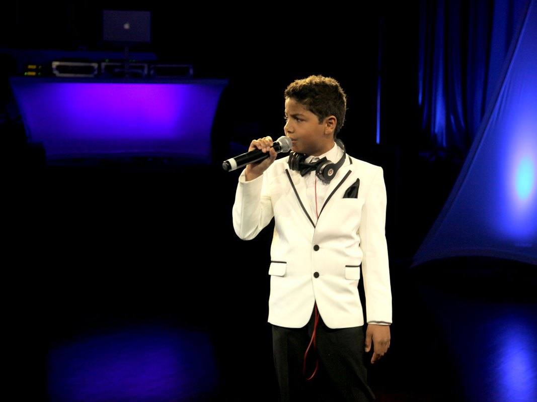 A speaker addressing guests with a handheld microphone under blue and violet lighting