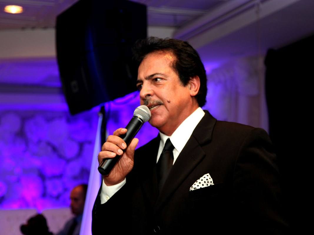 A speaker addressing guests with a handheld microphone at a Persian wedding reception in Toronto